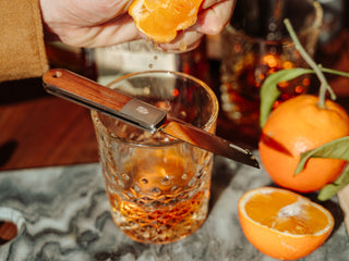 The Wayland classic Barlow EDC folding slip joint pocket knife resting on a cocktail glass.