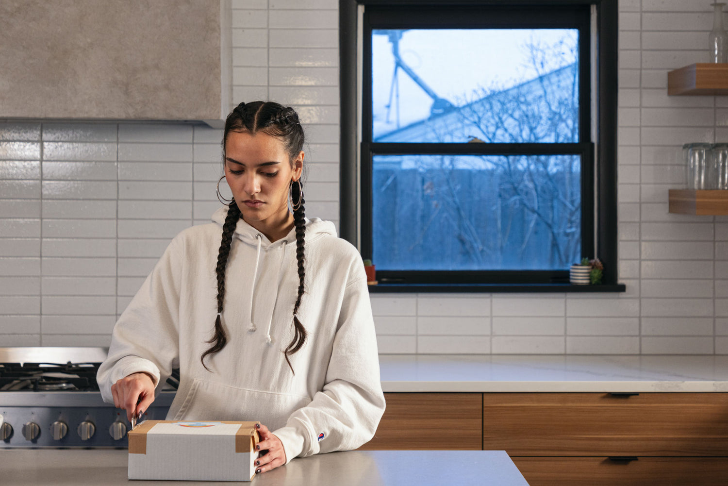 A women opening a box in her kitchen with the Abbey mini fixed blade knife.