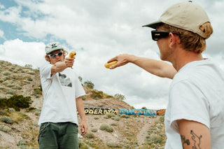 Two men pointing bananas at each other.