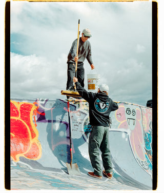 Two skateboarders cleaning out a pool to skate.