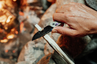 A man whittling down a stick with The James Brand Carter knife.