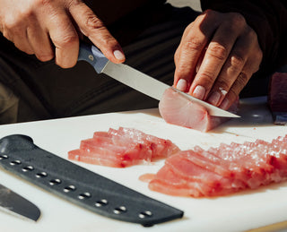 A man filleting sashimi on a cooler.