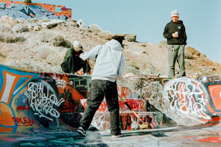 A group of skaters sweeping out a pool in the desert.