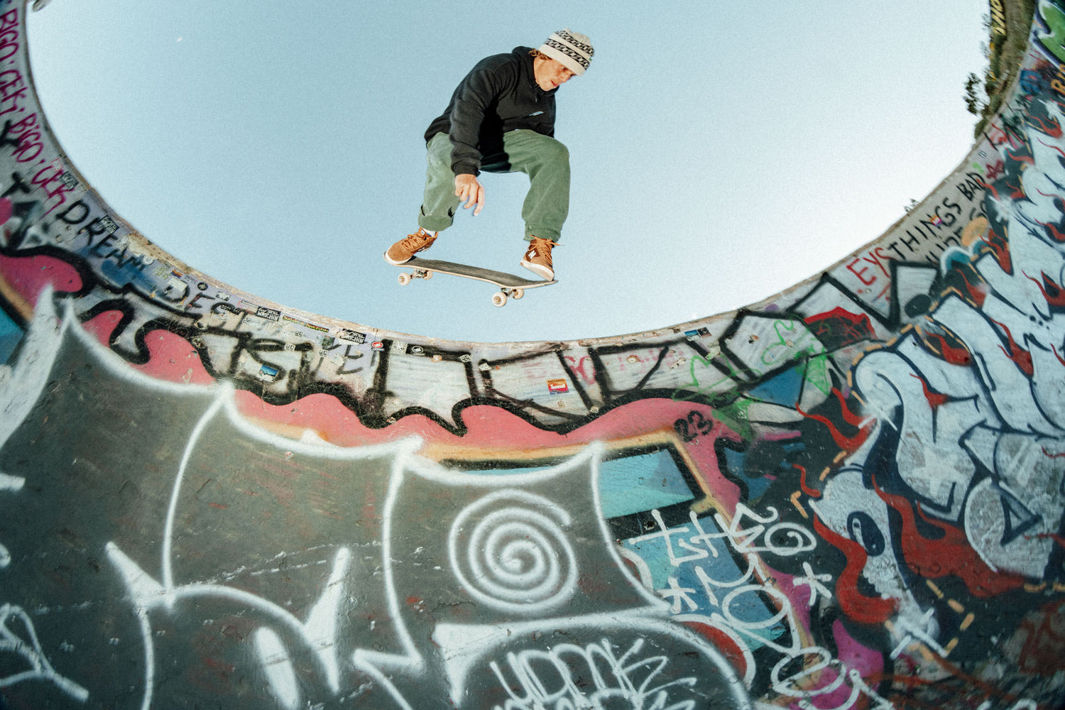 A skater riding above the coping in a graffiti covered pool.