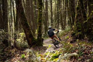 A mountain biker taking a turn on a trail in the forest.