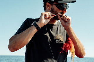 A fisherman preparing line using his teeth.