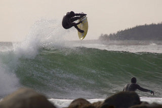 A surfer launching an air while surfing in Nova Scotia, Canada.