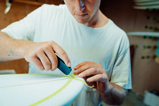 A surfboard shaper cutting tape using his Palmer EDC utility knife.