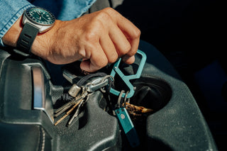 A person grabbing their carabiner keychain with keys and a small knife attached.