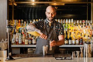 A Death & Co bartender pouring mixed into a tumbler.