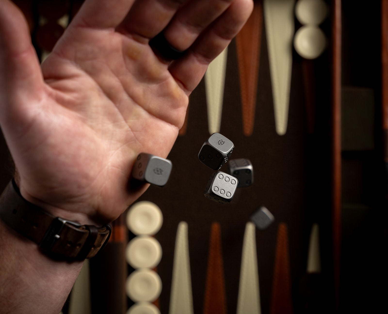 A man rolling the James Brand titanium dice onto a backgammon board.