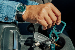 A man lifting his keychain EDCcarabiner from a car cup holder.