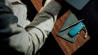 A utility knife and pen on a desk.