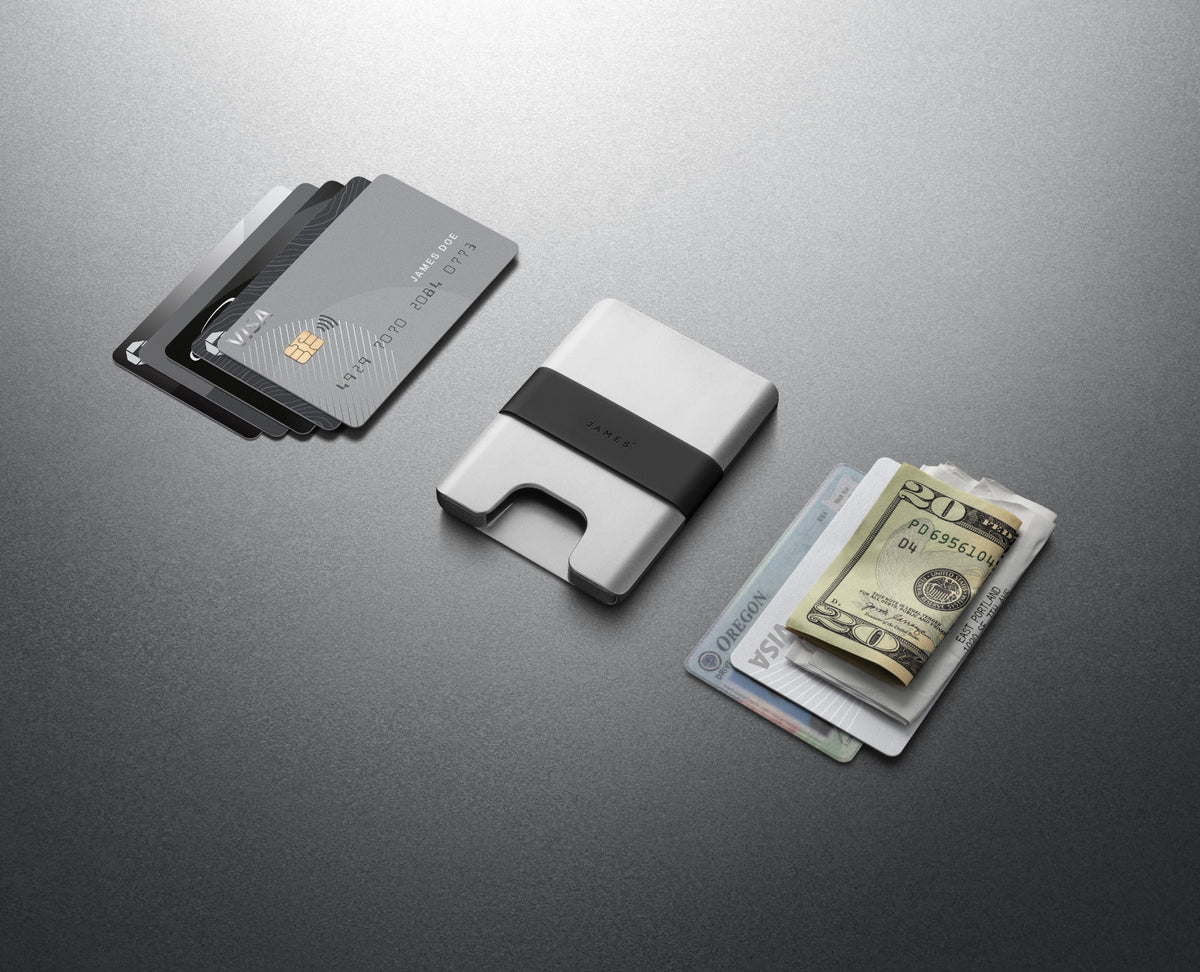 The Lowe minimalist card holder wallet in silver and black next to cash and credit cards.