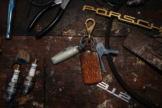 The Elko knife attached to a keyring on a workbench.