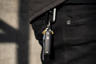 The Elko keychain pocket knife attached to a keyring with keys and a carabiner clipped to a belt loop.