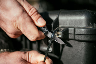 A man cutting a zip tie with his Elko keychain pocket knife.