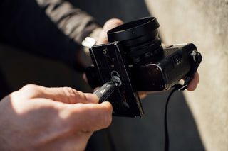A photographer using the pry bar of his Elko keychain knife to screw in a camera mount.