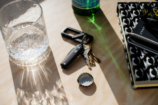 The Elko keychain pocket knife attached to a keyring with keys and a carabiner on a table.