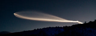 A rocket lifting off into space over a desert landscape.