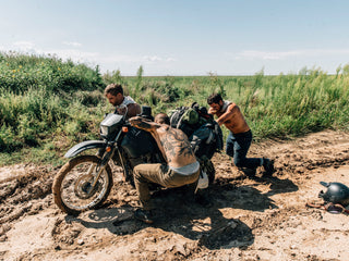 people helping motorcycle stuck in mud